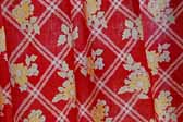 This photo shows a swatch of retro fabric with a country kitchen pattern on a red background, for your vintage trailer