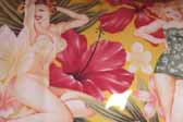 This photo shows a swatch of retro fabric with dreamy pinup girls in a tropical paradise, for your vintage trailer