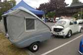 A vintage vw bug towing a compact fiberglass tent trailer