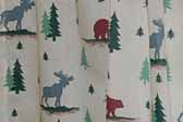 This photo shows a swatch of retro fabric with a moose, bear and woodsy cabin pattern, for your vintage trailer