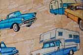 This photo shows a swatch of retro fabric with a vintage trailers, cars and pickup trucks pattern