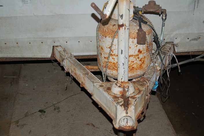 Rusty frame tongue and propane tank on a vintage Shasta trailer in storage yard