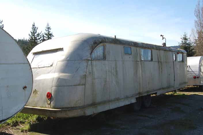 Dented and moss-covered Spartan Manor trailer stored in a vintage trailer Junkyard, is still restorable