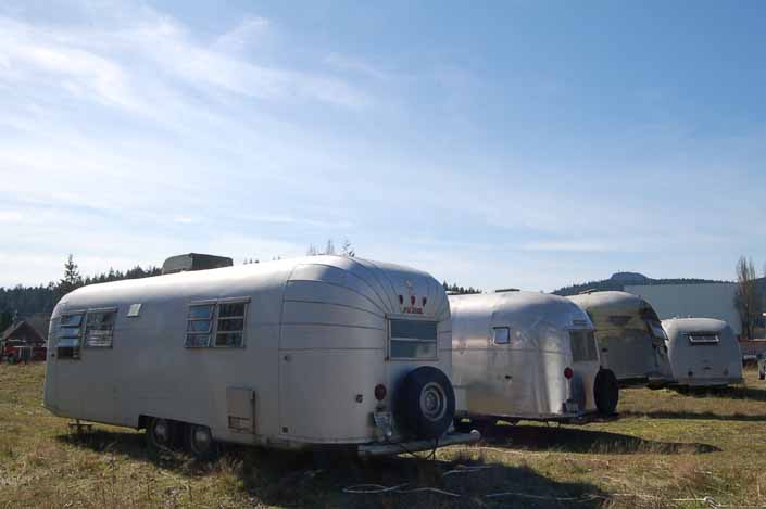 Vintage trailer junk yard has a row of restorable vintage aluminum trailers in storage