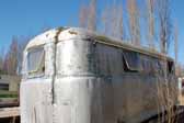 Rear end view shows unique modular side panels on a rare Palace trailer parked in a vintage trailer junkyard and awaiting restoration