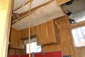 Detail photo shows delaminating but original wood ceiling panels and kitchen cabinets in a Palace trailer stored in a vintage trailer junkyard