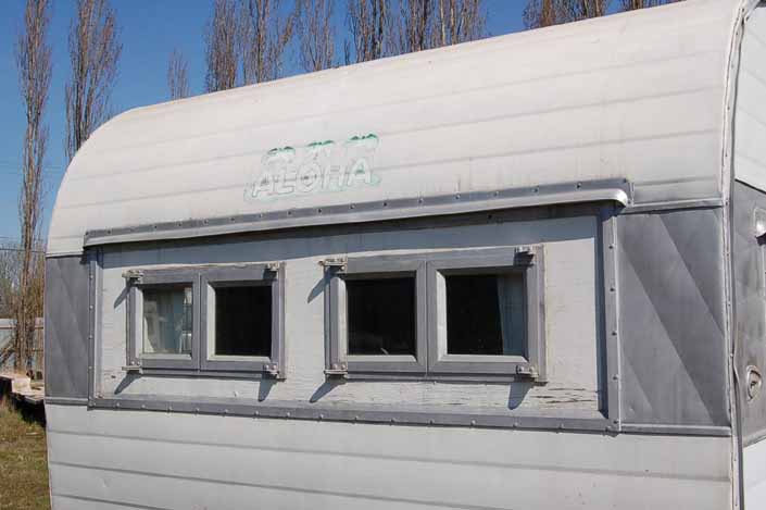 Vintage trailer storage yard has a vintage Aloha trailer with dinette window replaced by smaller front windows, available for restoration